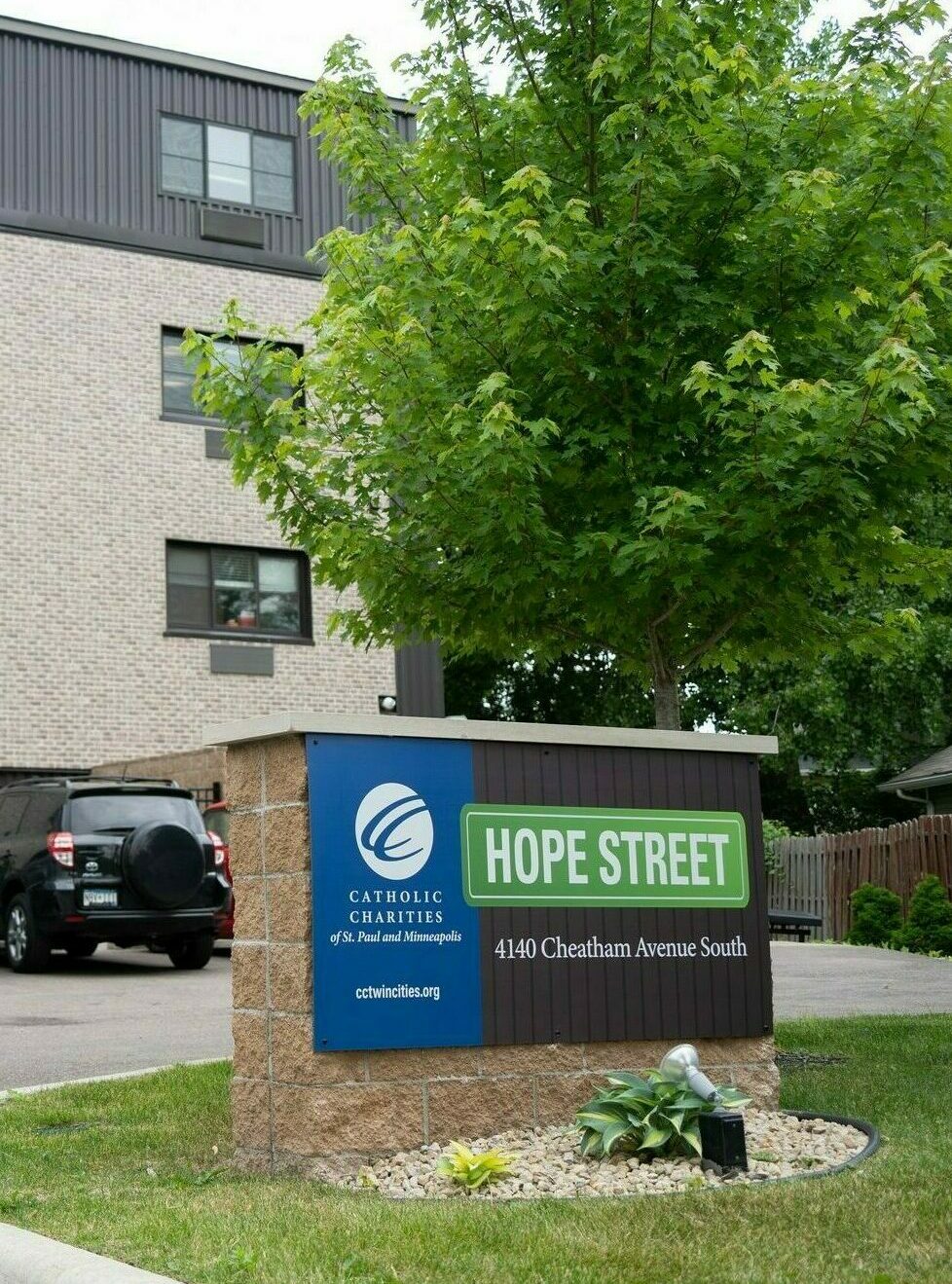 A building with a parking lot and a sign in front that says "Hope Street"