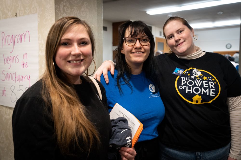 Three young white women staff member stand together at a community event